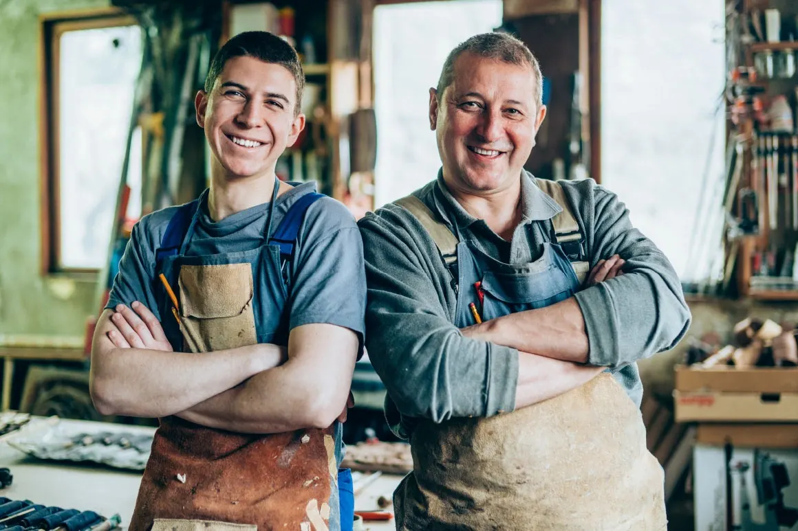 Two generations of a family business standing together in their workshop.